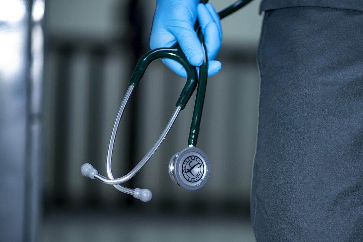 Zdravotník v rukavici drží stetoskop, symbol zdravotnej starostlivosti a medicíny.