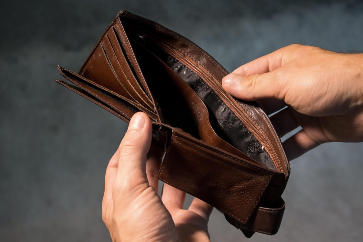 Prázdna hnedá peňaženka z blízka s rukami, ktoré ju držia, symbolizuje finančné problémy alebo nízky rozpočet.