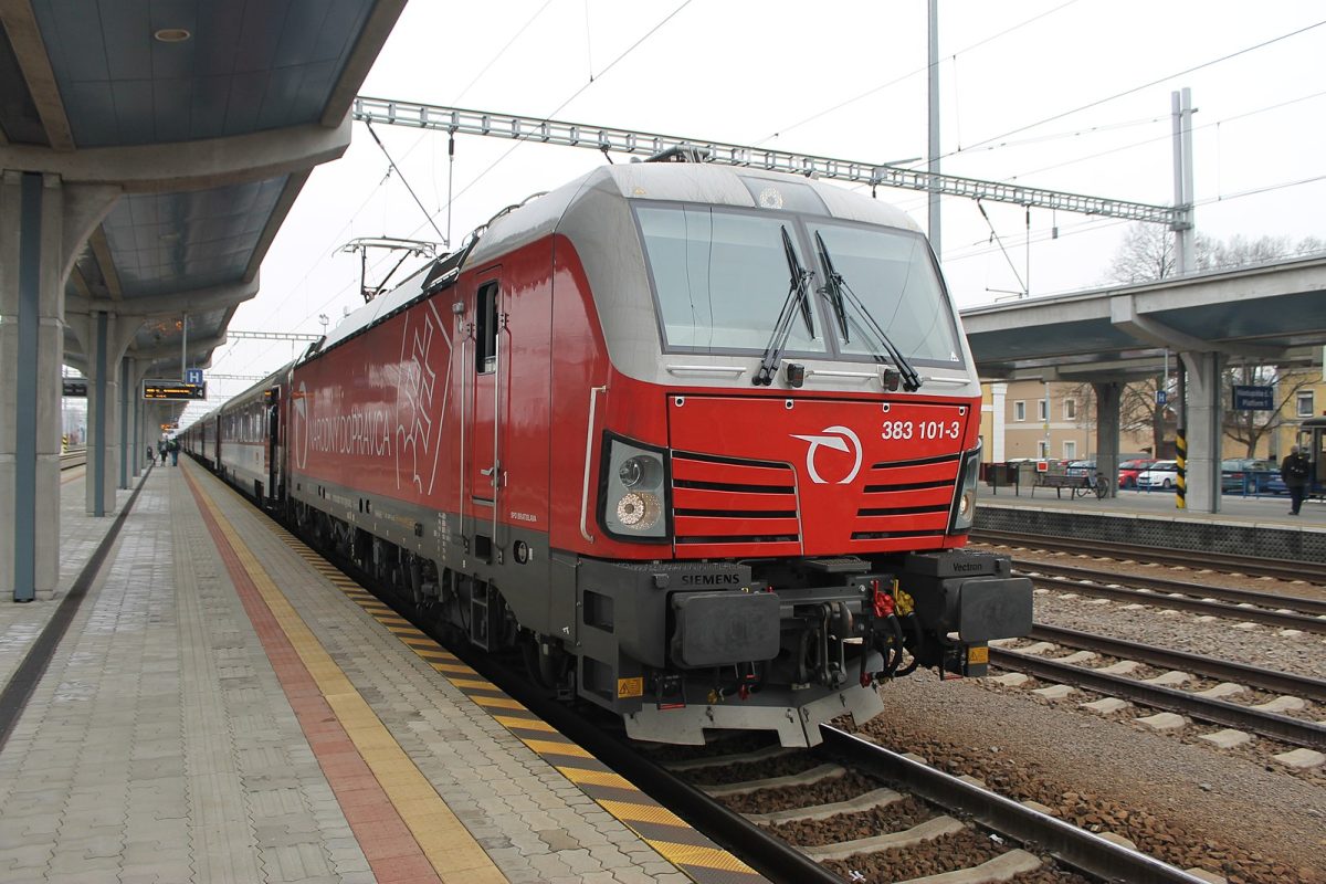 Červená elektrická lokomotíva na peróne stanice pripravená na odchod, moderný vlak v železničnej preprave.