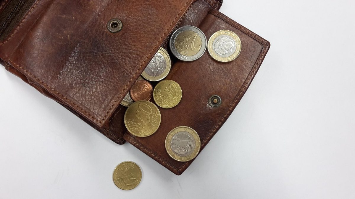 Kožená peňaženka plná euro mincí, rozložená na bielom pozadí.