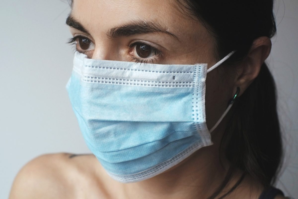 Osoba nosiaca modrú chirurgickú masku, zameraná na bezpečnosť a ochranu zdravia.